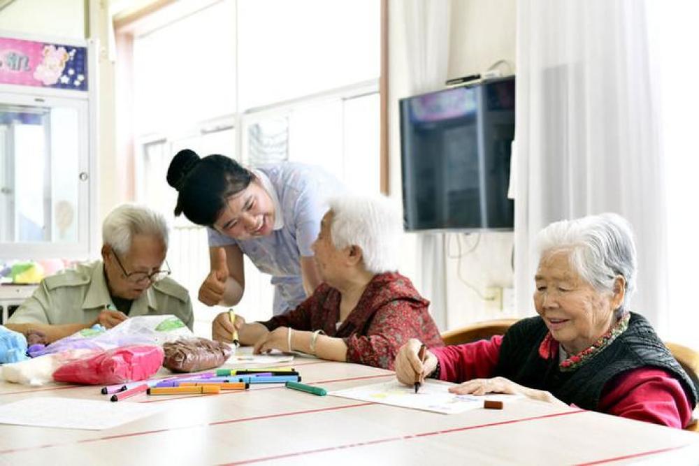 2024年5月25日，在山東省日照市東港區(qū)石臼街道日照幸福護(hù)理院，老人在工作人員的陪護(hù)下做填圖游戲。新華社記者 郭緒雷 攝